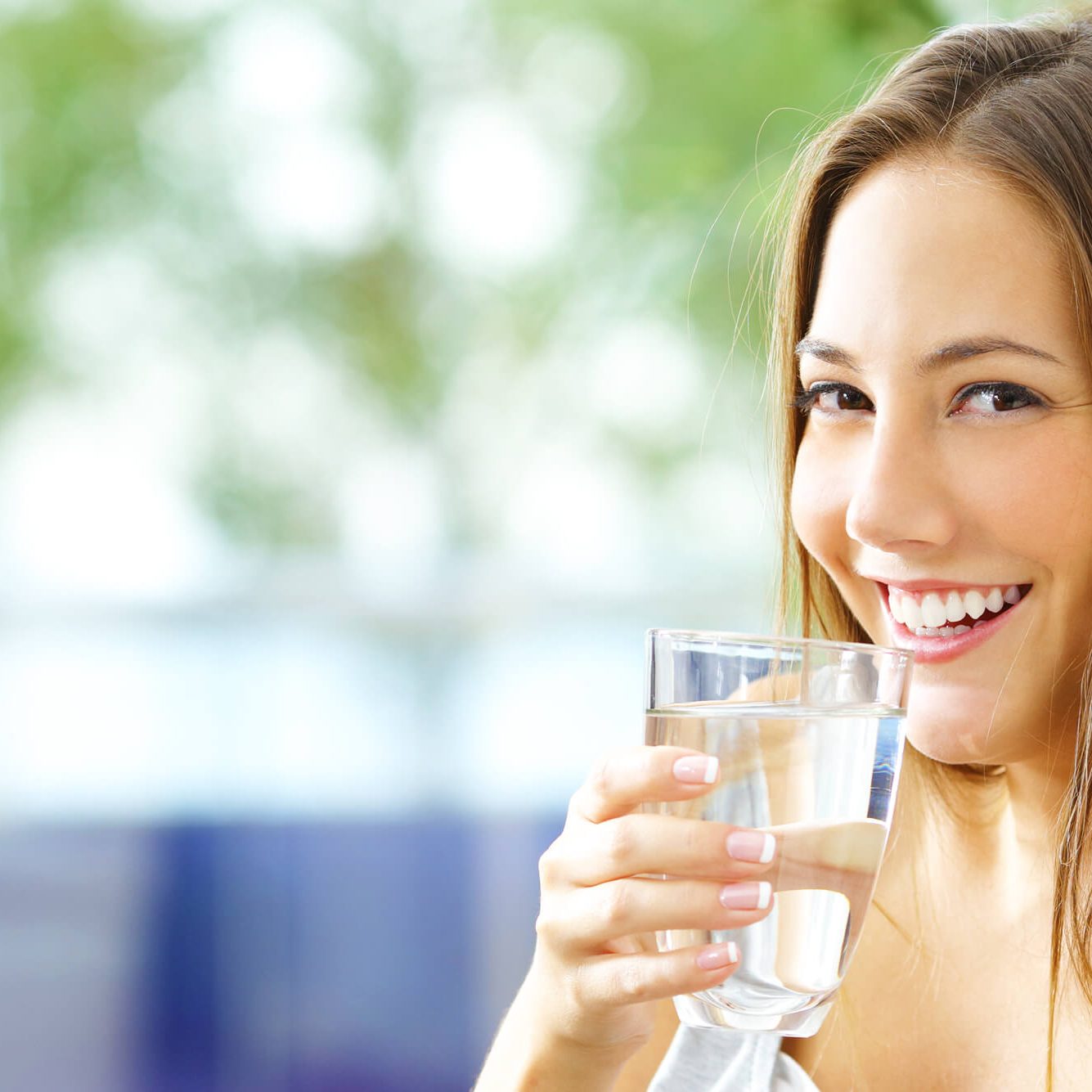 A Girl Showing Her Teeth While Smiling and Holding Glass of Water